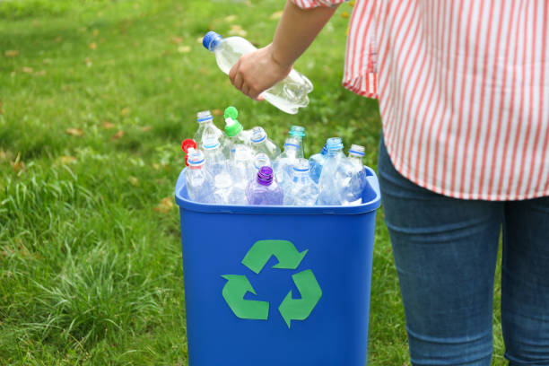 istock Woman throwing used bottle into trash bin outdoors, closeup. Plastic recycling 1352396931