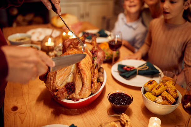 zbliżenie starszego mężczyzny rzeźbiącego świątecznego indyka podczas rodzinnego posiłku przy stole. - roast turkey turkey cutting roasted zdjęcia i obrazy z banku zdjęć