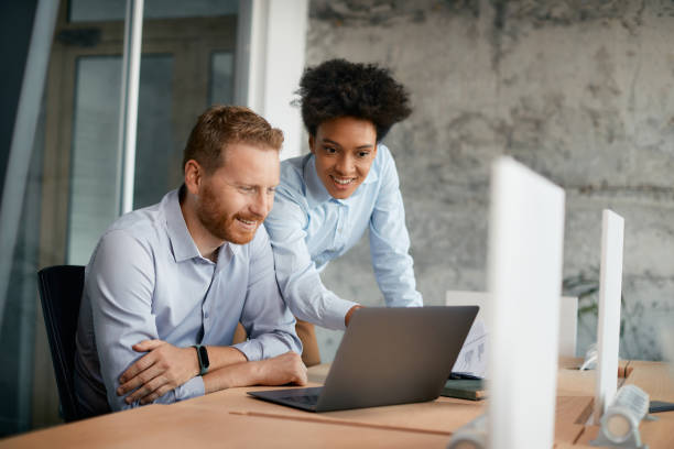 istock Happy business colleagues cooperating while using laptop in the office. 1352400109