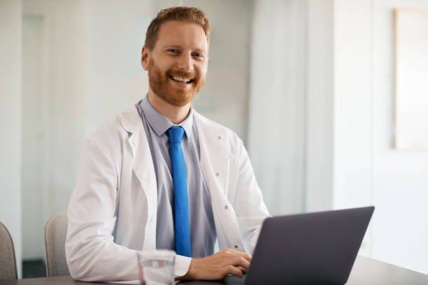 istock Happy doctor working on laptop at his office and looking at camera. 1352400407