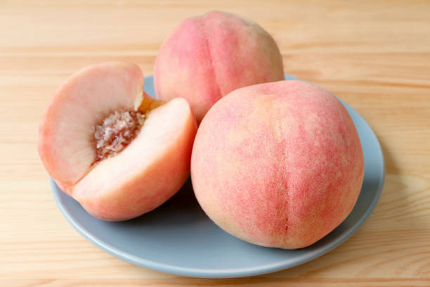 Fresh Ripe Peach Whole Fruits and a Cut Fruit on Blue Plate Served on Wooden Table