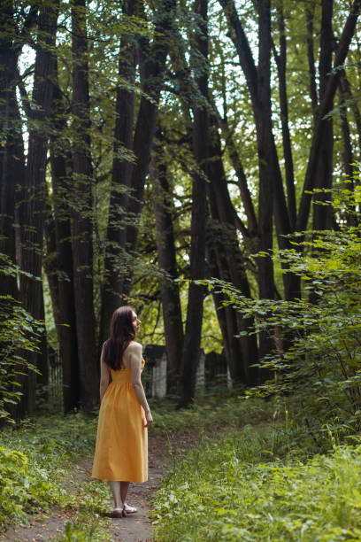 istock Attractive brunette in a dress walking through the forest 1352400822