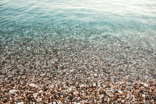 istock Sea stone pebble beach with colorful stones, transparent blue wave. 1352400959
