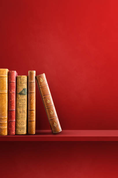 Row of old books on red shelf. Vertical background scene