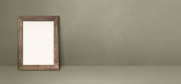 istock Wooden picture frame leaning on a grey wall. Horizontal banner 1352401189