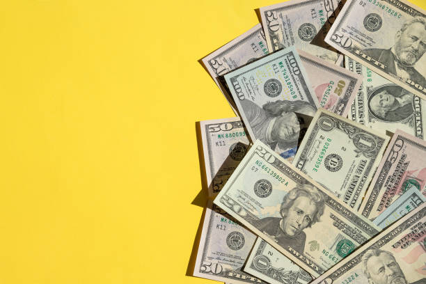 Scattered 100 American Dollars.Economic Crisis dollars money cash on yellow background. Background is banknote of US Dollar.many identical money notes in a mess.Copy space many identical money notes in a mess currency stock pictures, royalty-free photos & images