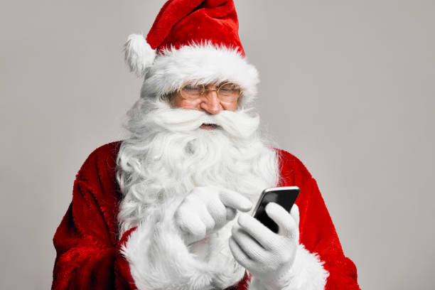 istock Caucasian Santa Claus in studio shot using mobile phone 1352403224