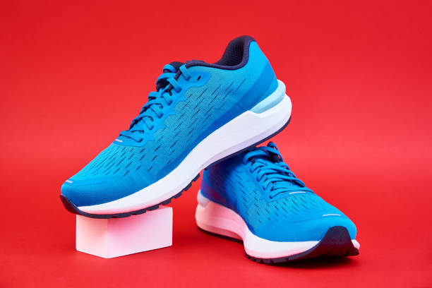 istock Pair of blue running sneakers on red background 1352403349