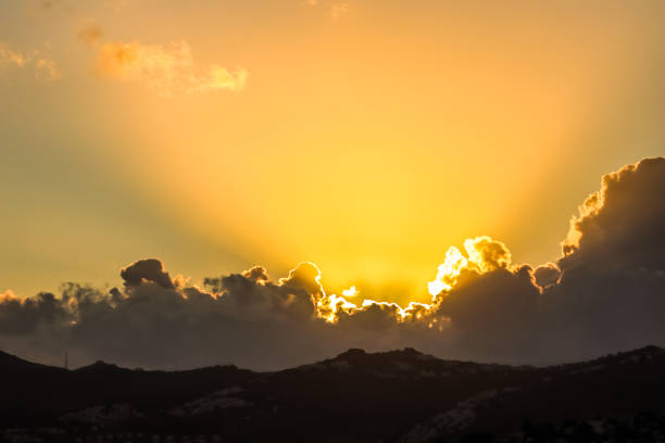 Background from a beautiful sunset with clouds and sunlights over mountanous coast. High quality photo