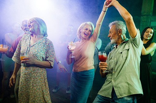 Happy senior couples having fun while dancing during nightlife in a disco.