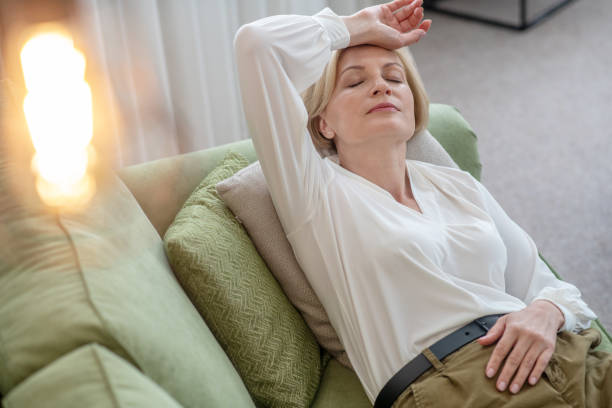 istock Blonde mid aged woman lying on the sofa and feeling bad 1352410429