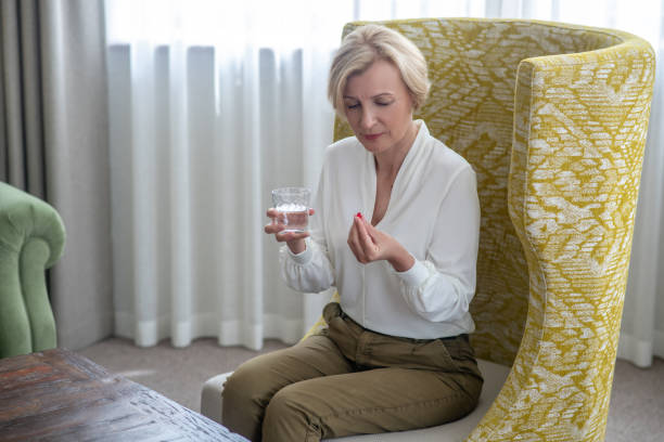 istock Blonde midaged woman feeling bad and taking a pill 1352410448