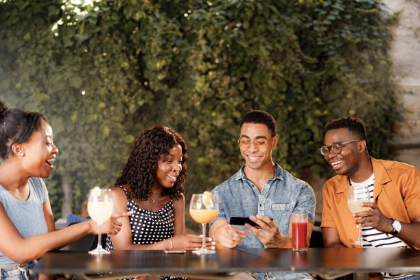 istock Happy black friends using mobile phone at cafe. 1352410465