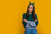 istock Sad and unhappy woman in christmas hat with crossed hands is posing isolated on yellow background 1352410622