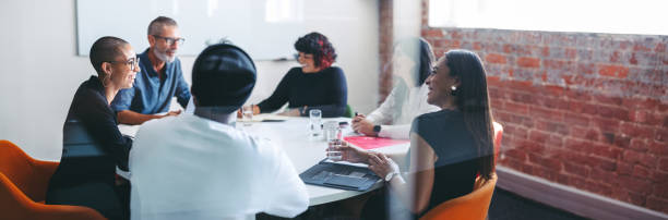 smiling businesspeople sitting together in a meeting room - group of people occupation business people imagens e fotografias de stock