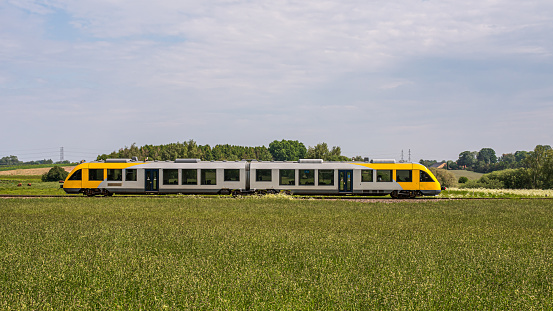 a local yellow train in a green field on its way to Hillerod, Denmark, June 8, 2021