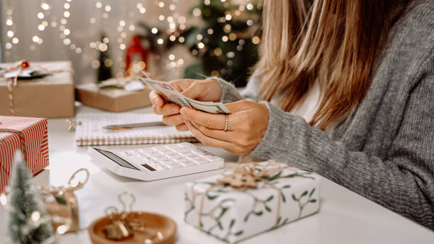 istock Girl counting US Dollar bills, using calculator, and writing expenses. Woman doing budget, estimating money balance for shopping spree. Female accountant paying taxes. Girl counting Christmas gifts 1352413412