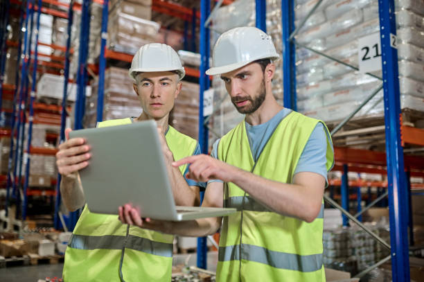 istock Two men looking at laptop deciding work question in warehouse 1352413769