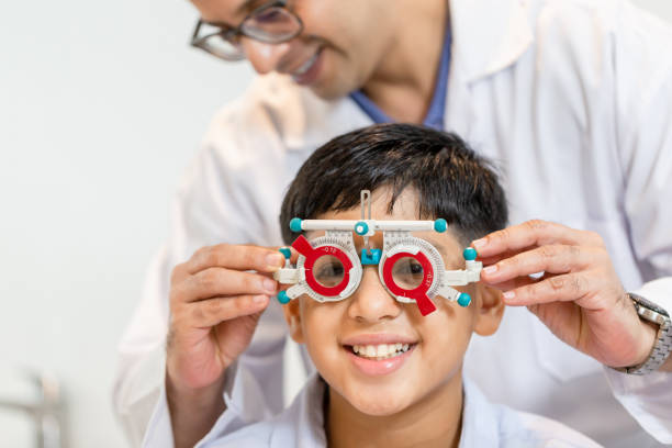istock Smiling Indian-thai boy choosing glasses in optics store, Boy doing eye test checking examination with optometrist using trial frame in optical shop 1352413942