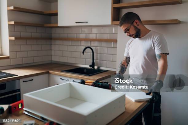 A Tattooed Worker Is Setting Up A Drawer In His Kitchen He Is Using A Pencil To Mark The Wooden Material Stock Photo - Download Image Now