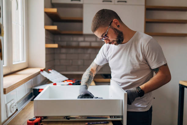 istock A carpenter with protective gloves on his hands fixes a drawer in the kitchen with an electric screwdriver. 1352414790