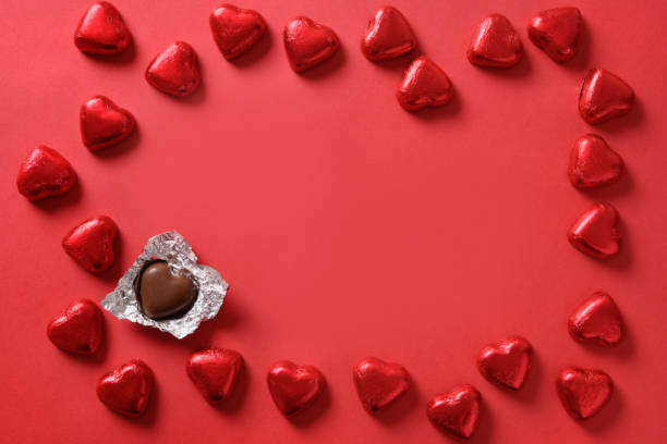 istock Valentine's day romantic chocolate sweets as heart in red foil as frame on red. 1352414932