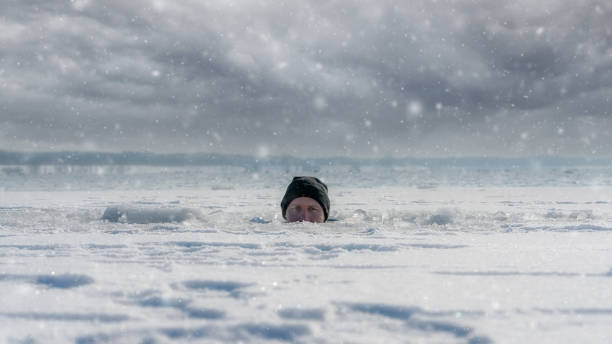 A man looking out of an ice hole while having an ice bath A man looking out of an ice hole while having an ice bath in a frozen lake ice bath stock pictures, royalty-free photos & images