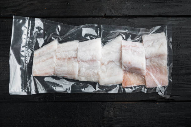 istock Haddock fish skinless in vacuum pack, on black wooden background, top view 1352415159