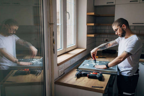 istock Side view, an electrician fixes a stove in the kitchen. His reflection is seen in the mirror. 1352415179