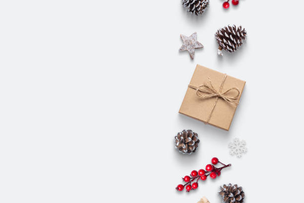 istock Christmas composition with copy space. Gift, pine cones, rose hip, snowflake and decorations in vertical line on white background 1352415781
