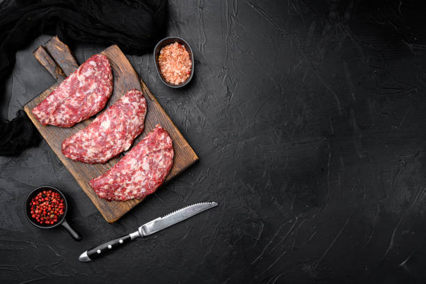 istock Raw beef patty, on black dark stone table background, top view flat lay, with copy space for text 1352418373