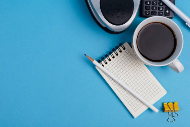 istock Flat lay of minimal workspace desk with notebook, calculator and coffee copy space on blue tone 1352418398