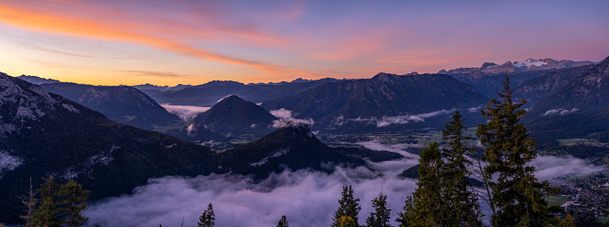 Panorama Photo of Awesome Mountain Landscape With Some Fog in Valley, Forests and Peaks at Early Morning Sunrise in Autumn, Dachstein Glacier in Background