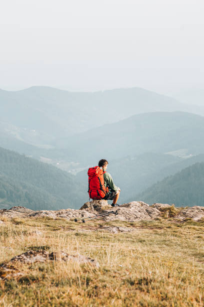 istock Hiker relaxes at viewpoint on grassy mountain ridge 1352420156
