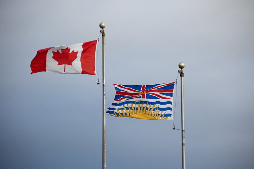Canadian National flag and British Columbia provincial flag waving in wind