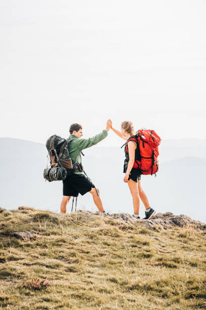 istock Hiking friends relax on grassy mountain ridge 1352420368