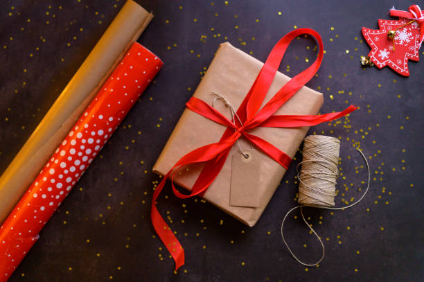 fond de noël avec boîte cadeau, ficelle de ficelle, rouleaux de papier et ornements en rouge. préparation des vacances. vue de dessus - wrapped package string box photos et images de collection