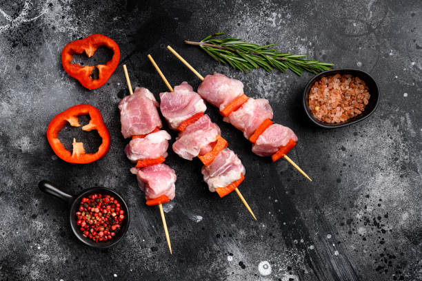 istock Raw pork shish kebab. BBQ meat with vegetables, top view flat lay, with copy space for text, on black dark stone table background 1352422537