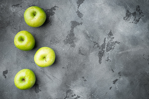 Several ripe green apples set, on gray stone table background, top view flat lay, with copy space for text