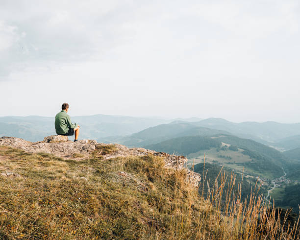 istock View of hiker relaxing on grassy mountain ridge 1352422898