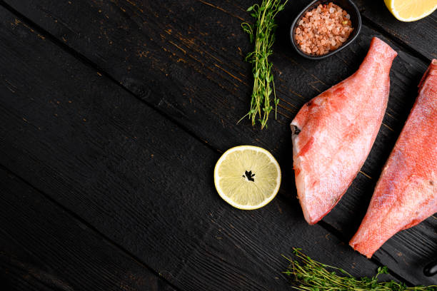 Raw fish perch without a head, on black wooden table background, top view flat lay, with copy space for text Raw fish perch without a head set, on black wooden table background, top view flat lay, with copy space for text fillet red snapper fish raw stock pictures, royalty-free photos & images