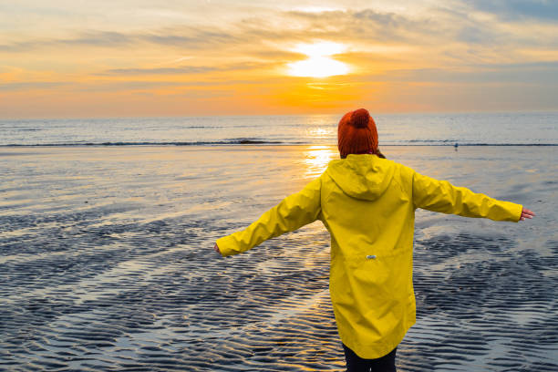 woman enjoys sunset on beach - duitse noordzeekust stockfoto's en -beelden