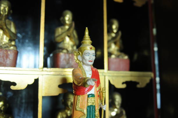 istock Small Asian statue of monk with pointing gesture in Thai temple 1352423552