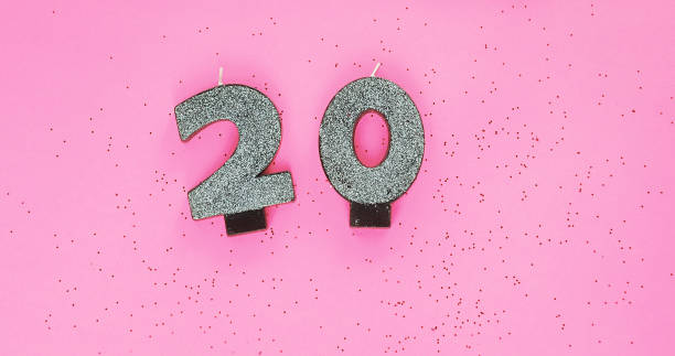 istock 20, silver candles on pink background with glitters. Festive colorful background. 1352424478