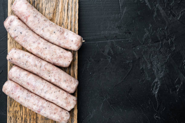 istock Traditional raw chicken sausages, top view with space for text, on black background 1352425753