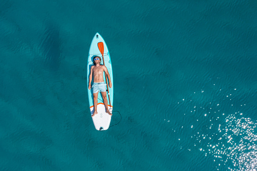 He lies down on paddle board and enjoys relaxation on tropical turquoise lagoon