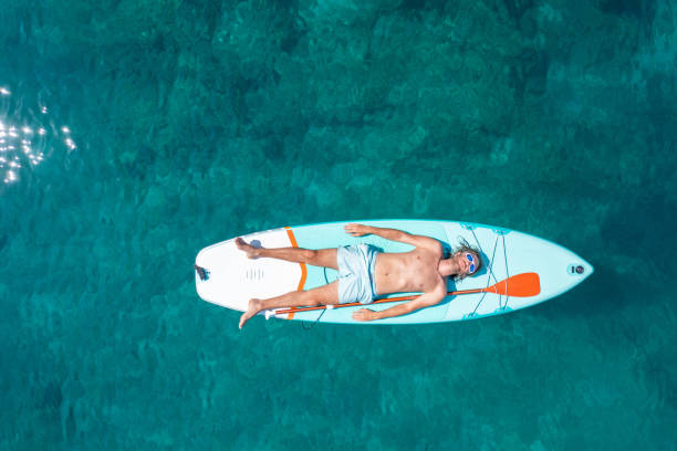 Drone view of man lying on a stand up paddle