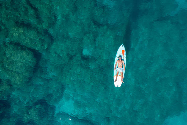 istock Drone view of man lying on a stand up paddle 1352426254