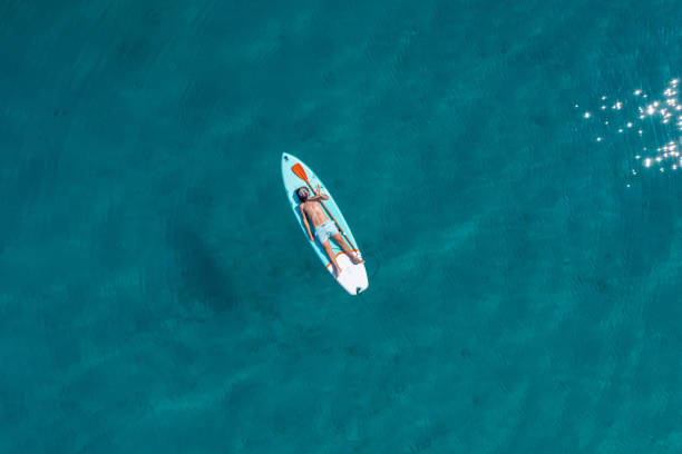 istock Drone view of man lying on a stand up paddle 1352426353