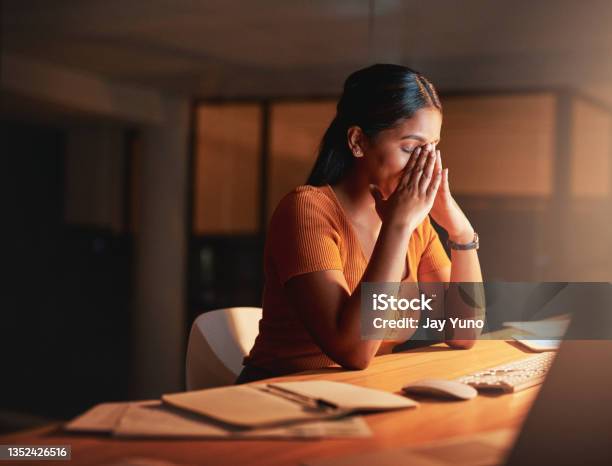 Shot Of An Attractive Young Businesswoman Sitting Alone In The Office At Night And Feeling Stressed Stock Photo - Download Image Now